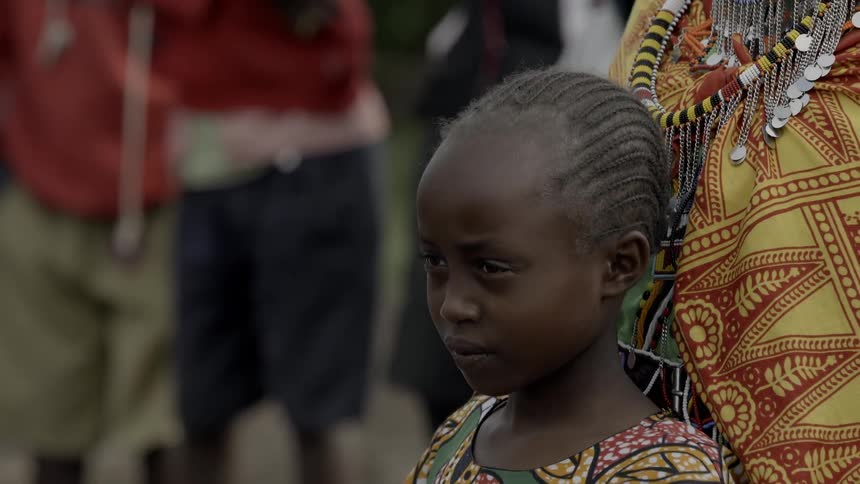 A maasai woman hugs a young girl outdoors