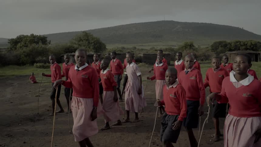 Maasai in uniforms and costumes perform a dance outside
