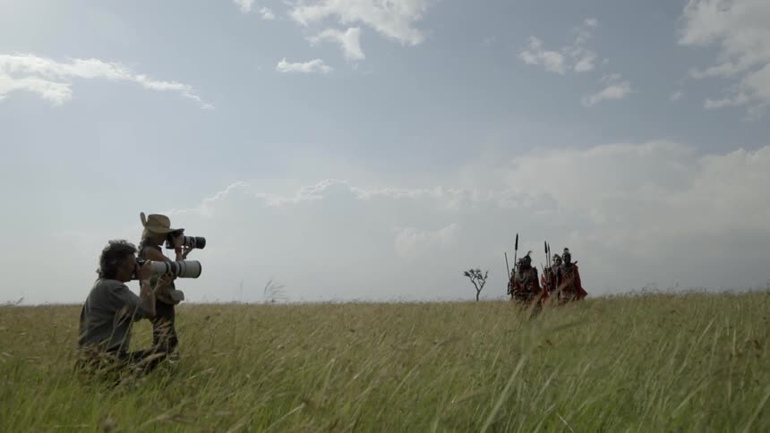 Two photographers are taking photos of a group of african tribesmen during the day