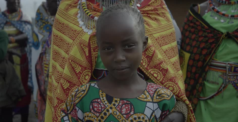 An african girl is held by an adult as she stares forward