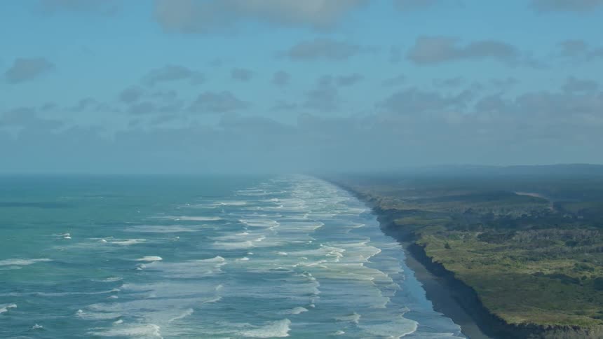 Waves are rolling toward the beach on a sunny day