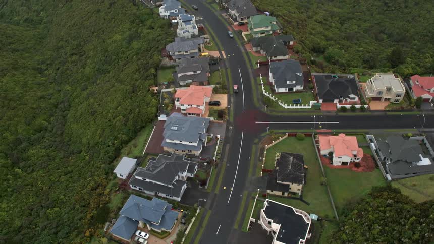 Houses sit atop a hill near a winding road
