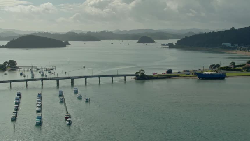 Boats sit parked in the water by a bridge