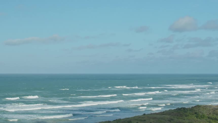 Waves are rolling toward the beach on a sunny day