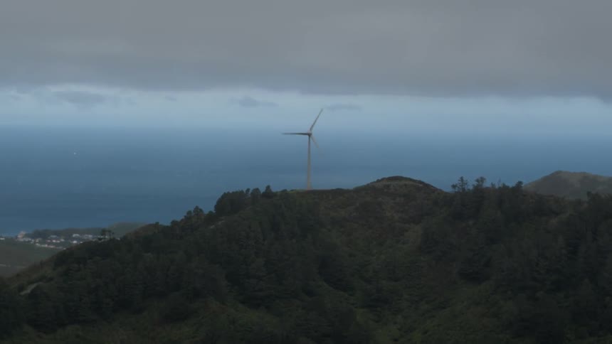 A windmill spins on top of a hill