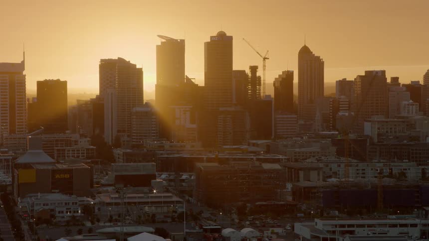The sun is setting beyond high rises in a city