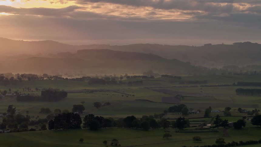 Fog hangs over a rural valley at dawn