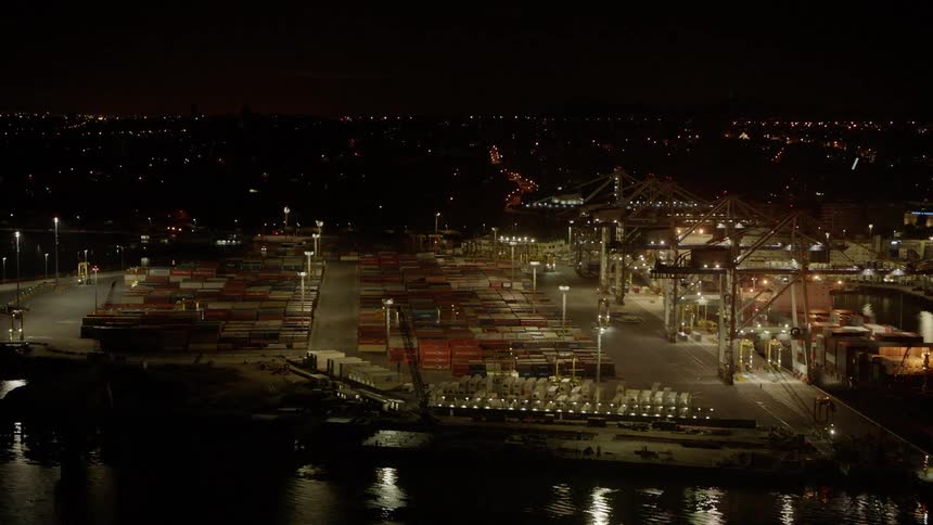Transport vehicles travel on a dock with shipping containers