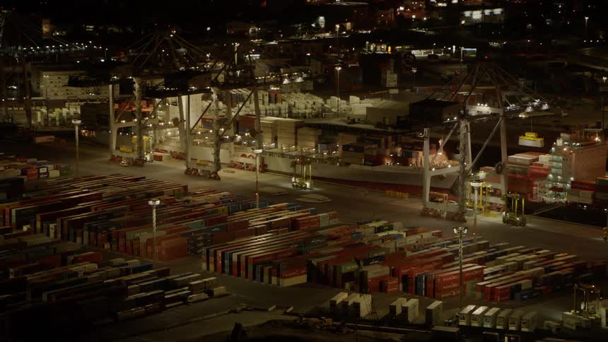 Transport vehicles travel on a dock with shipping containers