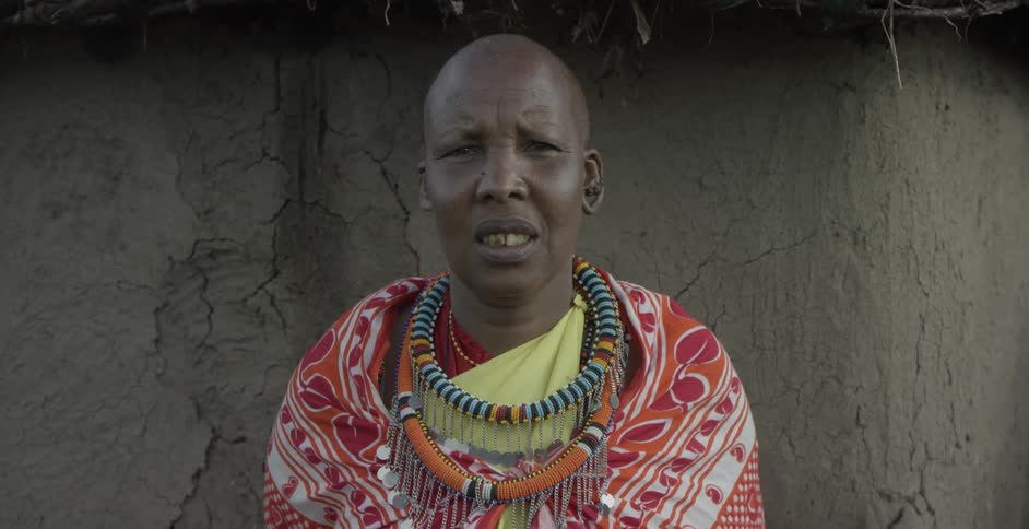 A maasai stands with large necklaces around his neck