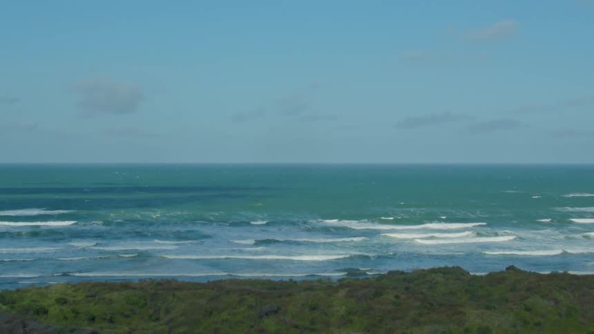 Waves are rolling toward the beach on a sunny day