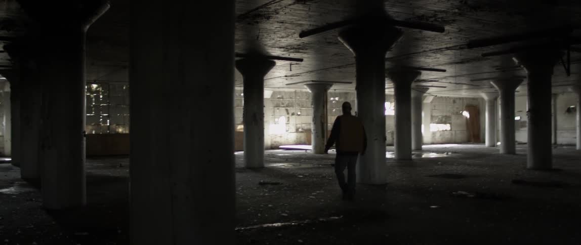 A person is walking down the dark parking lot