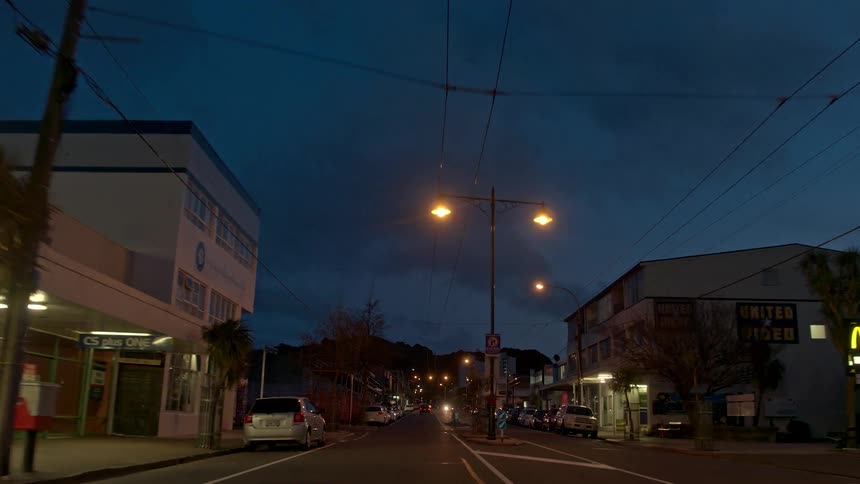 A person is riding a bicycle on a busy town street at dusk