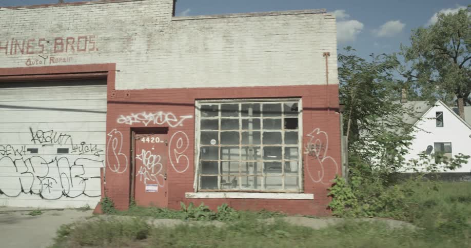 Abandoned building with some graffiti painted on it  next to a home in a small town