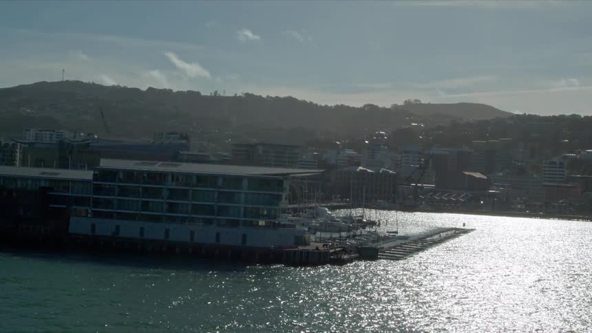 The docks by the city has bright sunlight reflecting off the water