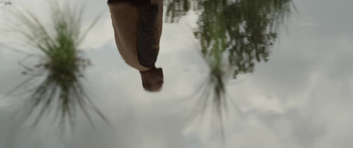 A man walks along a large puddle on the pavement
