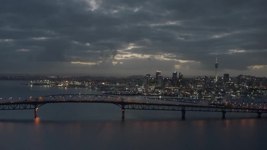 Dark clouds hang over a city and harbor at dusk