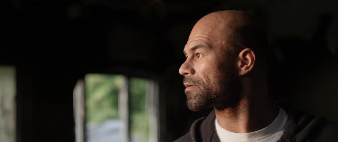 A man smiles as he turns his head while standing inside a home during the day