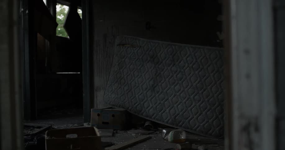 An old mattress is leaning against the wall of an abandoned house