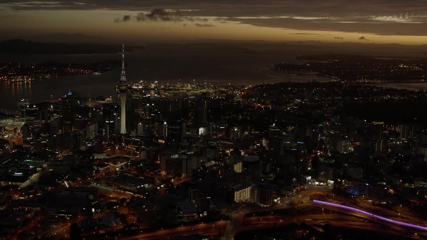 Lights illuminate buildings and streets in a city at dusk
