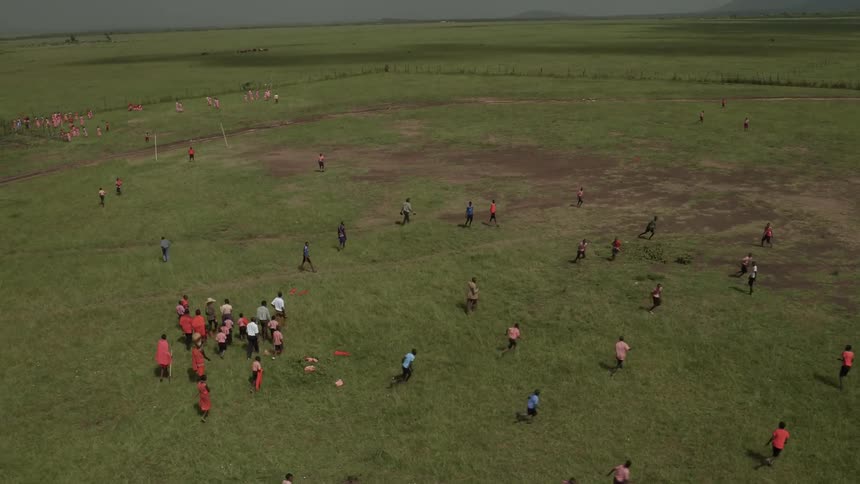 Group of people play soccer on a grassy field