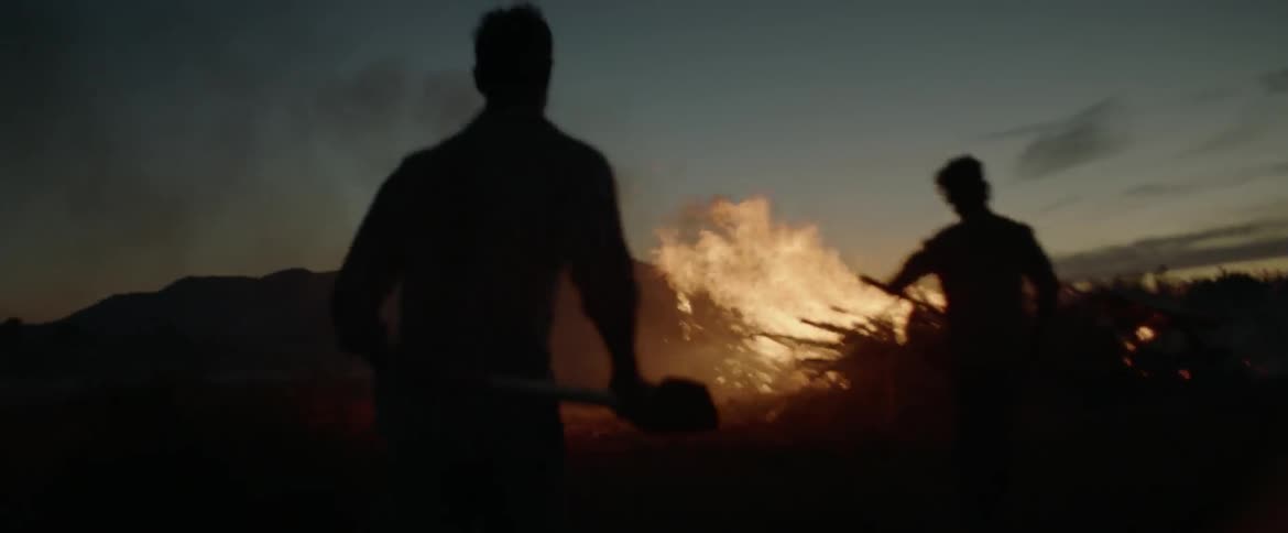 Two people are rushing towards a fire with shovels
