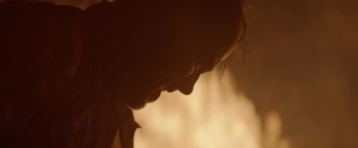 A man is furiously digging dirt into a large fire