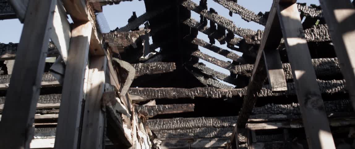 The exposed frame of an old building shows fire damage