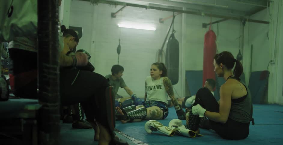 People sitting around in a gym area while some are preparing for their workouts