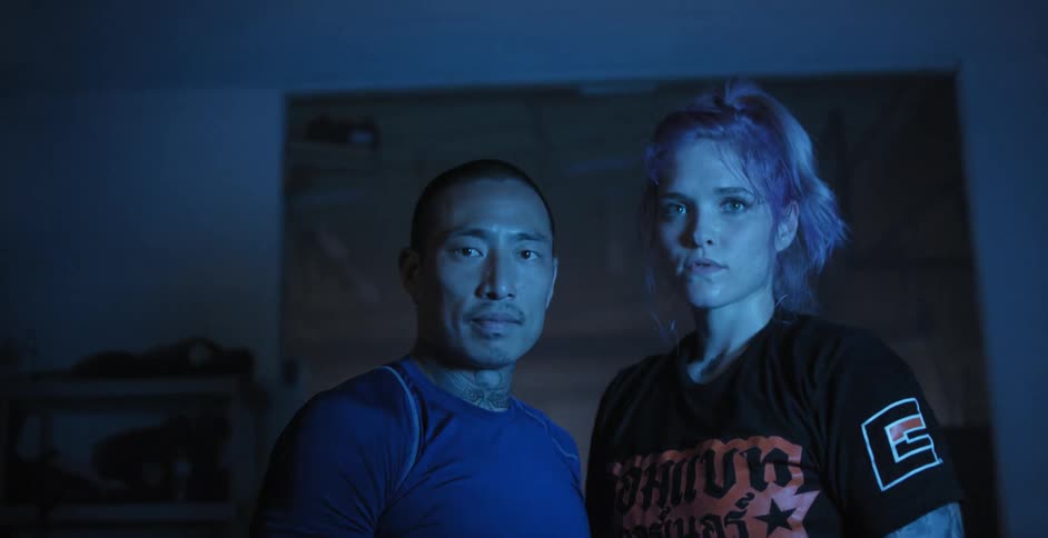 Man and woman stand in dark fitness room