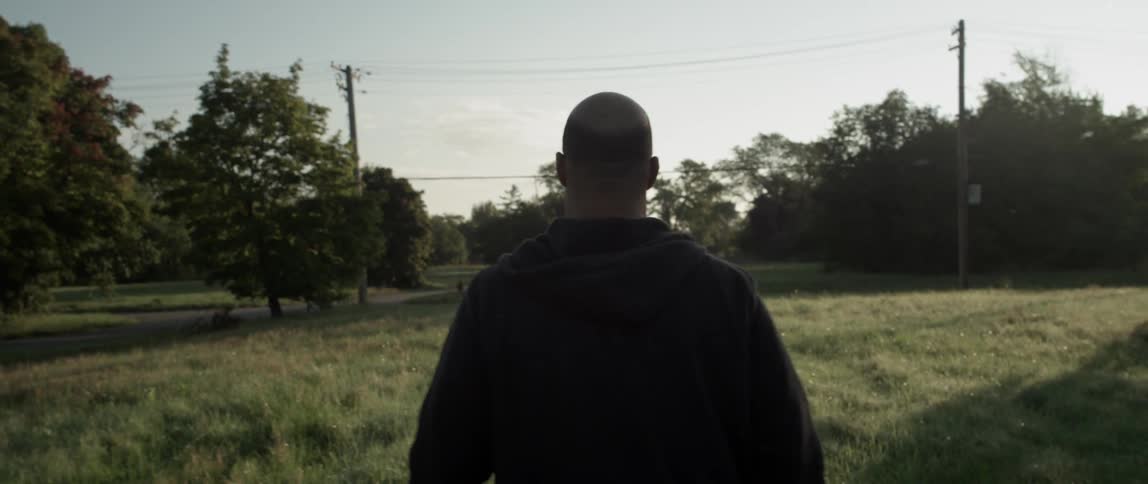 A man walks around in a field as the sun shines