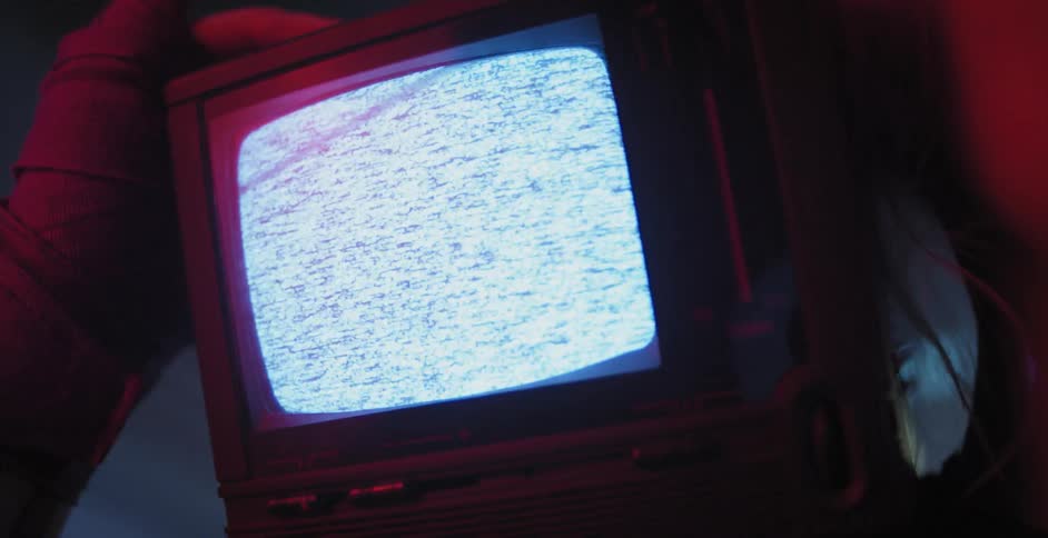 A small television monitor is lit up with static on the screen