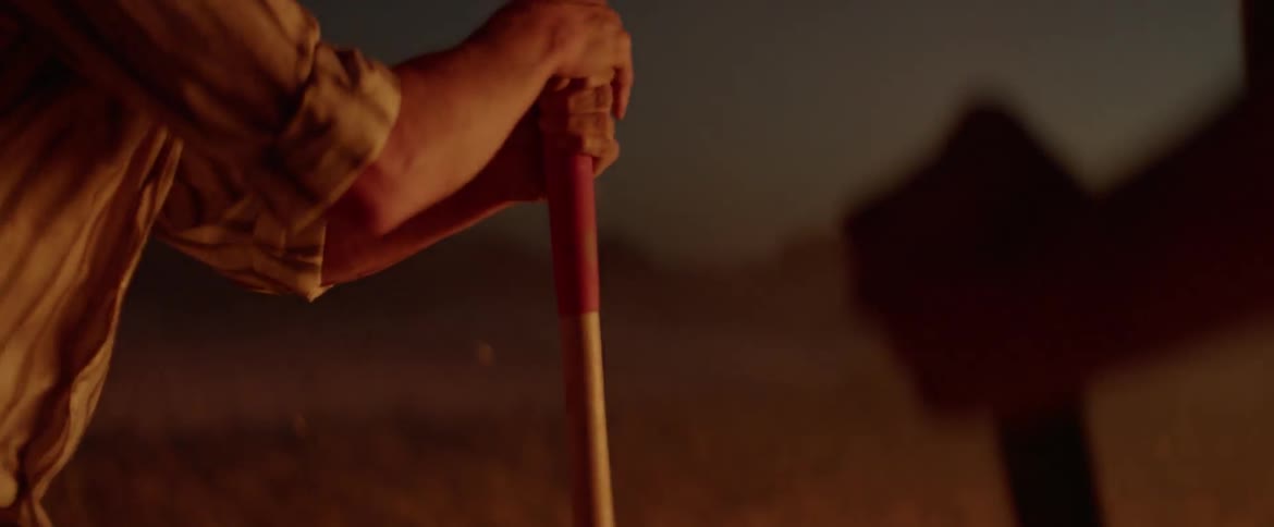 Two men are digging with shovels and throwing dirt onto a large fire
