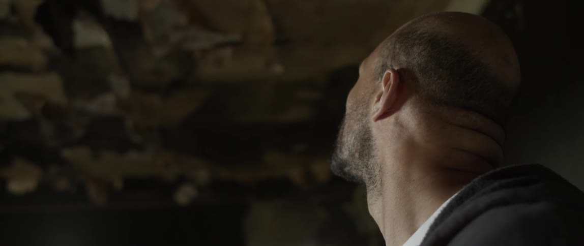 A man is looking up in the dark house