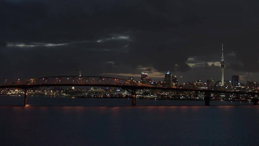 Lights illuminate a harbor and city skyline at dusk