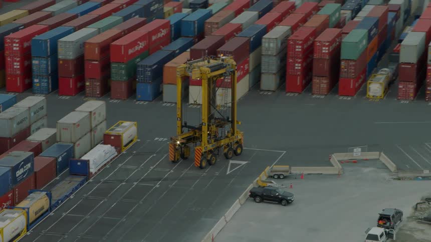 A transport vehicle travels on a dock with shipping containers