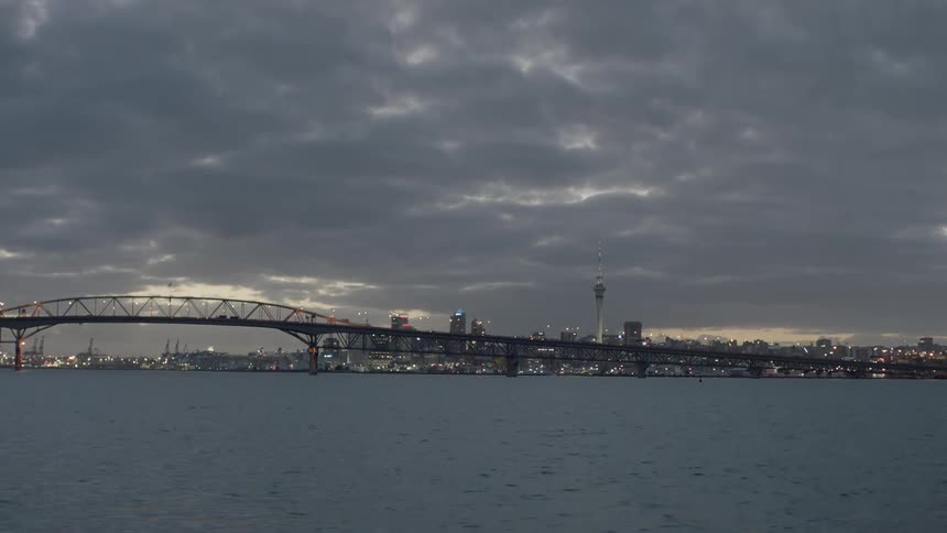 Vehicles pass on a city bridge as clouds hang overhead