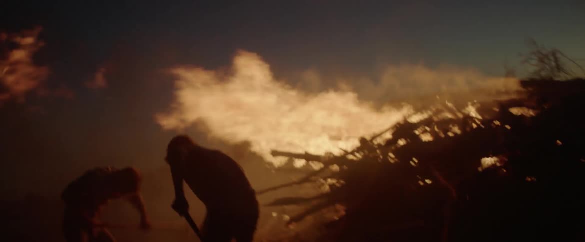 Two people are shoveling dirt on a large fire trying to put it out