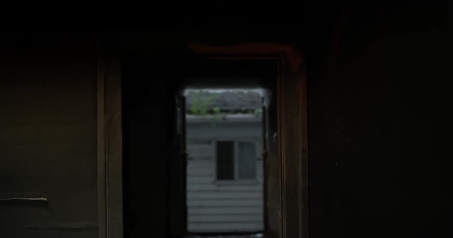 A shadow sways in a tattered doorway
