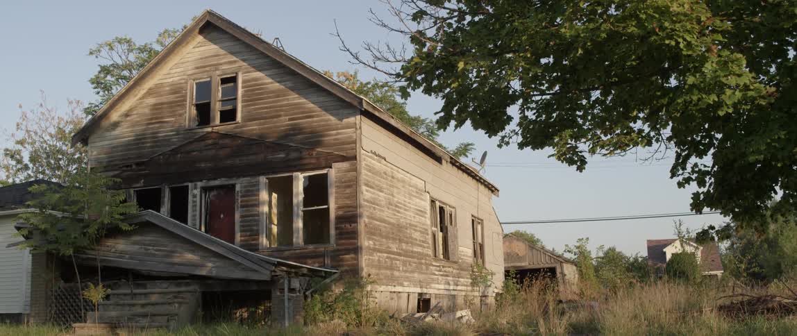 A man walks towards an abandoned house