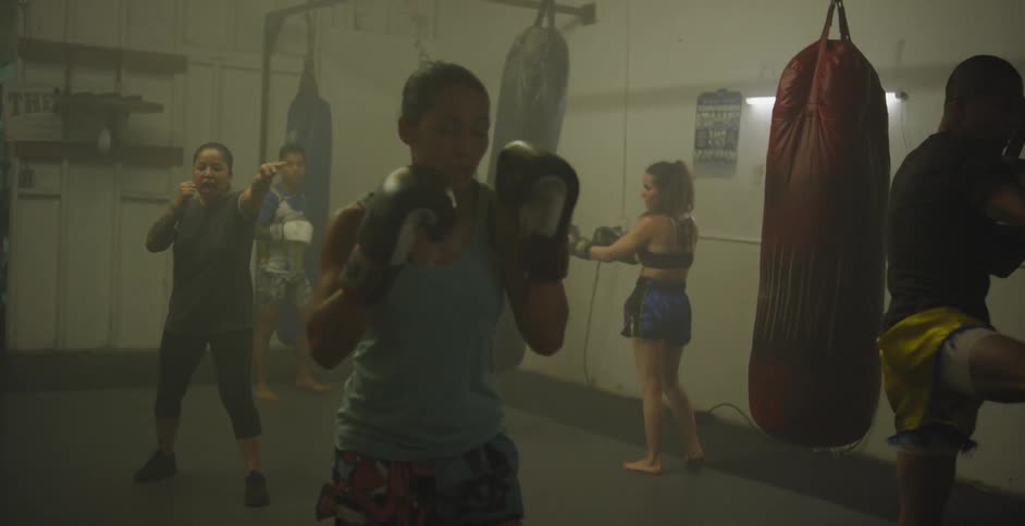 People kick and hit punching bags in a gym