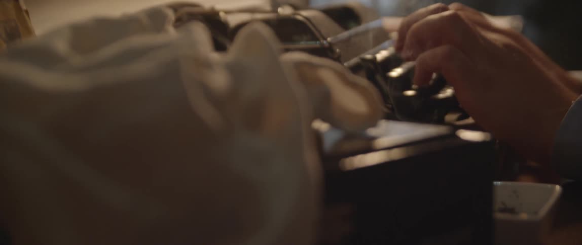 Person typing on a typewriter as smoke rises