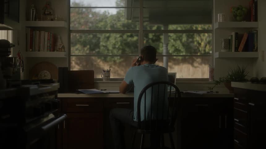 A man sits at a desk talking on the phone