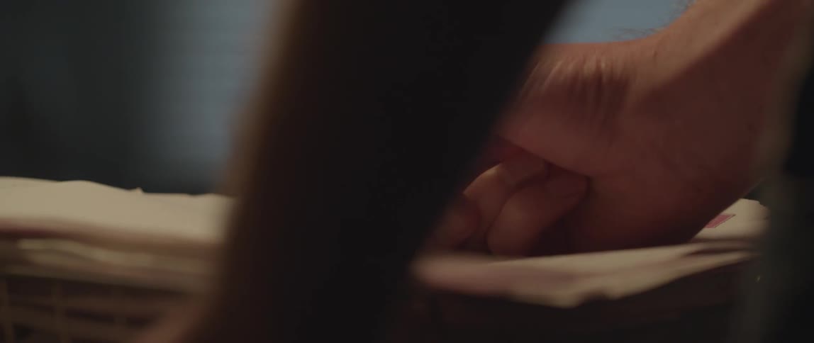 A hand holding a pencil and writing on some paper