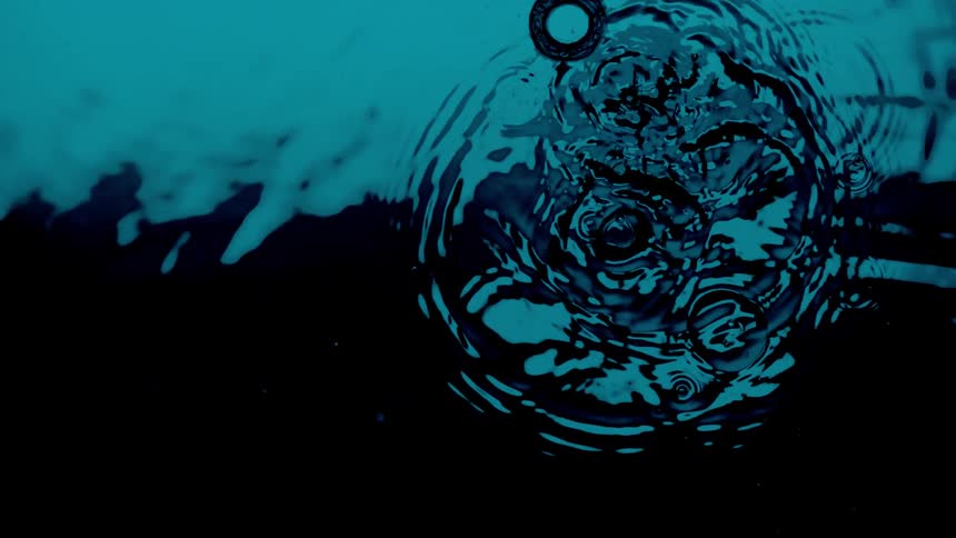 Drops of water are falling into a dark pool