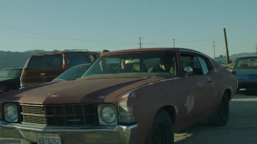 A man parks an old car in the dirt