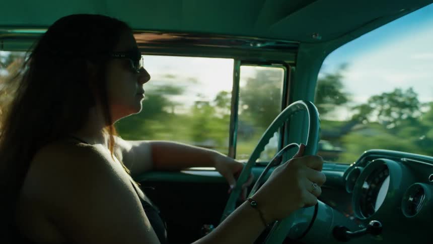 Woman drives antique car on a sunny day