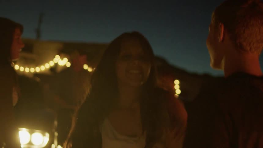 A group of being are gathered together dancing at night outdoors