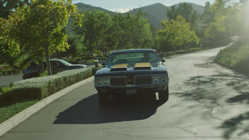 A blue hot rod drives down the road