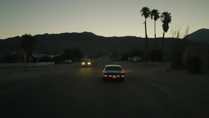 A car is traveling down a street at dusk